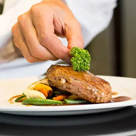 The Rio Grande Chef Created Meals, chef garnishing a plate.